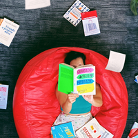 woman on red bean bag reading book in spanish