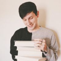 boy holding a stack of books and smiling