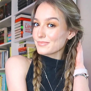 headshot of teen girl with light brown hair in 2 braids posing in front of book shelf