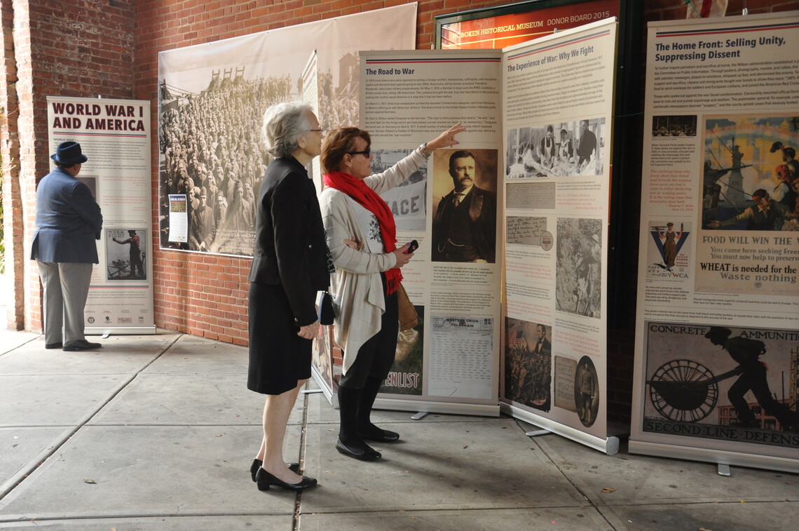 Two women looking at a WWI panel display by the Gilder Lehrman Institute of American History