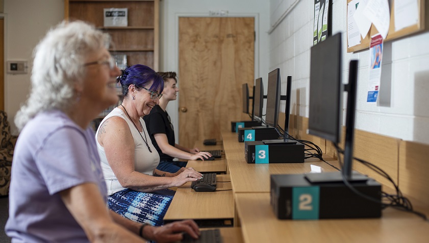 Three women of varying ages using the internet at the Illinois Valley computer stations.