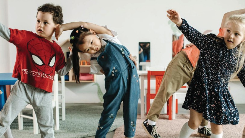 A room full of toddlers doing stretches and dancing.