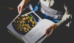 woman's hands holding open cookbook in dark room